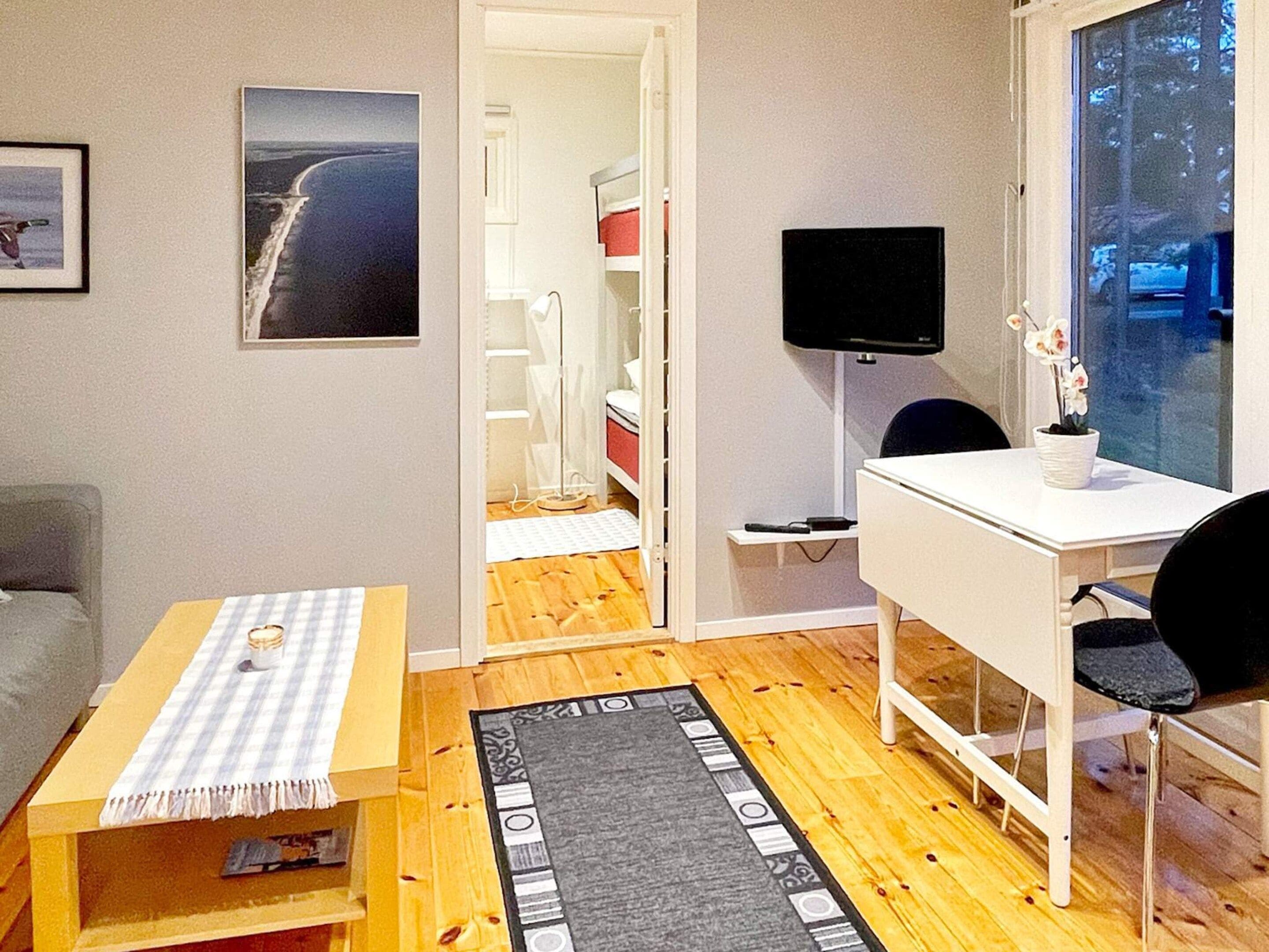 A compact living space with a desk, chair, and a television. A small table with a checkered tablecloth is placed in the foreground.