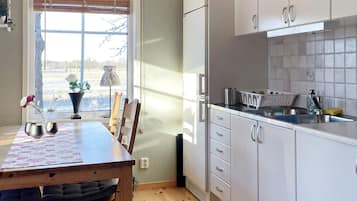 A kitchen with white cabinets, a wooden table, and a window with blinds.