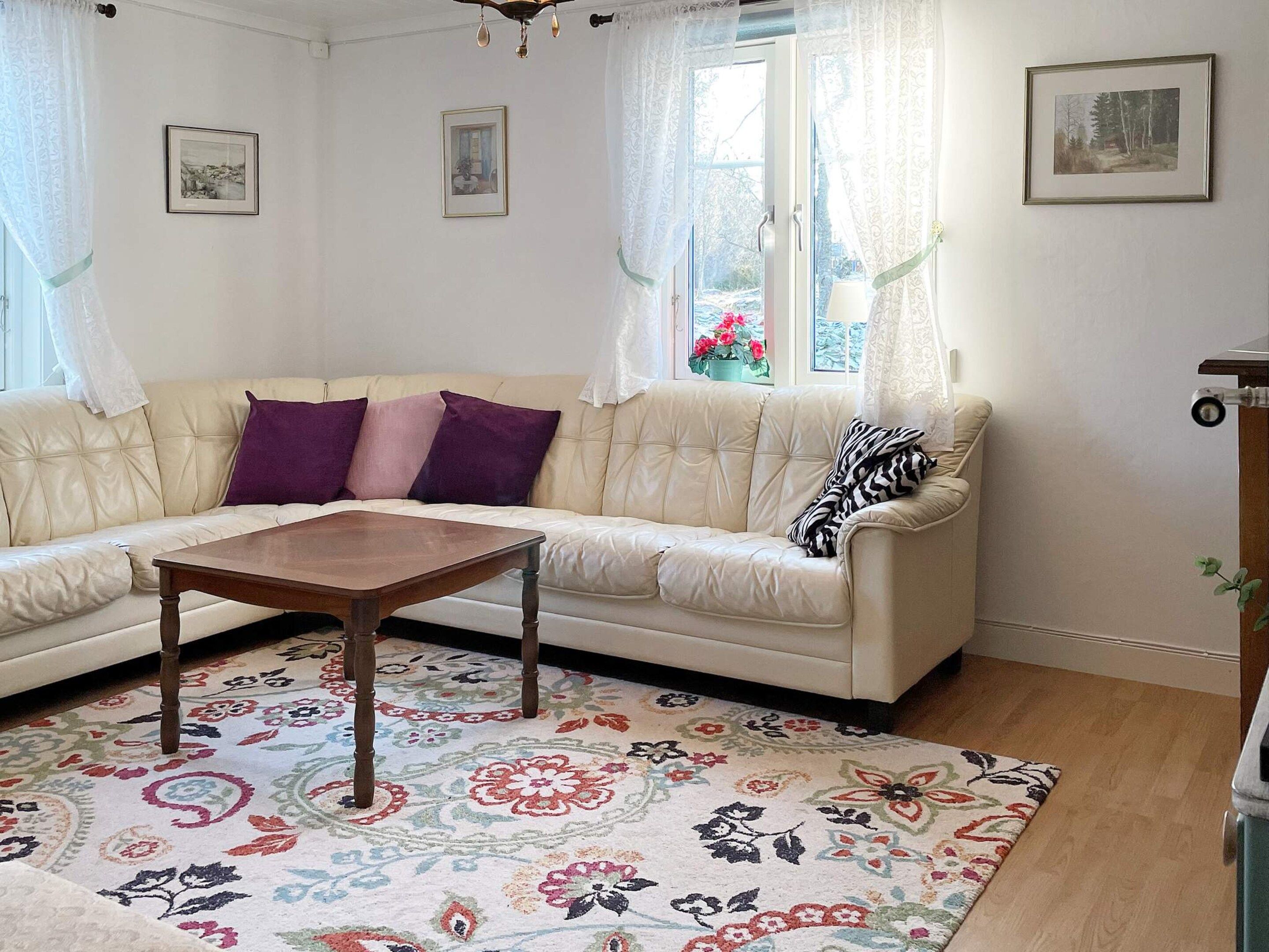 A living room with a beige sofa, a wooden coffee table, and a floral patterned rug.