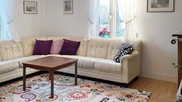 A living room with a beige sofa, a wooden coffee table, and a floral patterned rug.