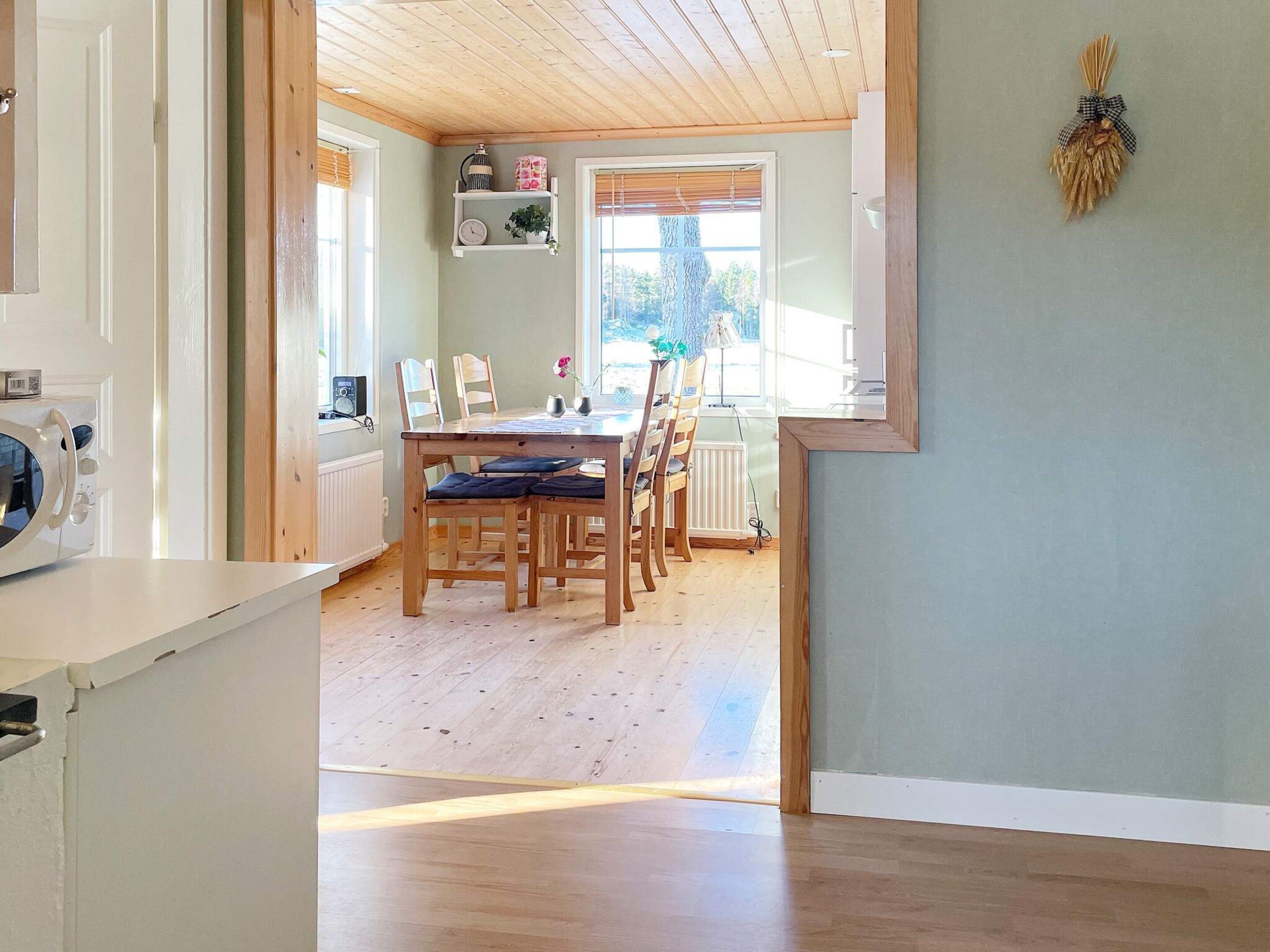 Un comedor con una mesa y sillas de madera, un microondas blanco y una ventana con persianas.