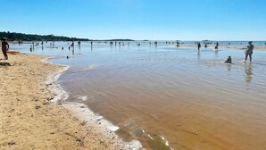 A beach with people in the water and on the sand, clear skies, and a calm sea. - 6 Person Holiday Home in Lidkoping (Lidköping)