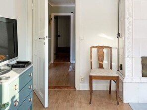 A room with a television, a wooden chair, a blue dresser, and a hallway leading to another room. - 6 Person Holiday Home in Lidkoping (Lidköping)