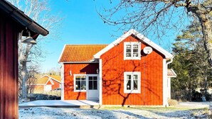 A red wooden house with a tiled roof, white windows, and a visible satellite dish. - 6 Person Holiday Home in Lidkoping (Lidköping)