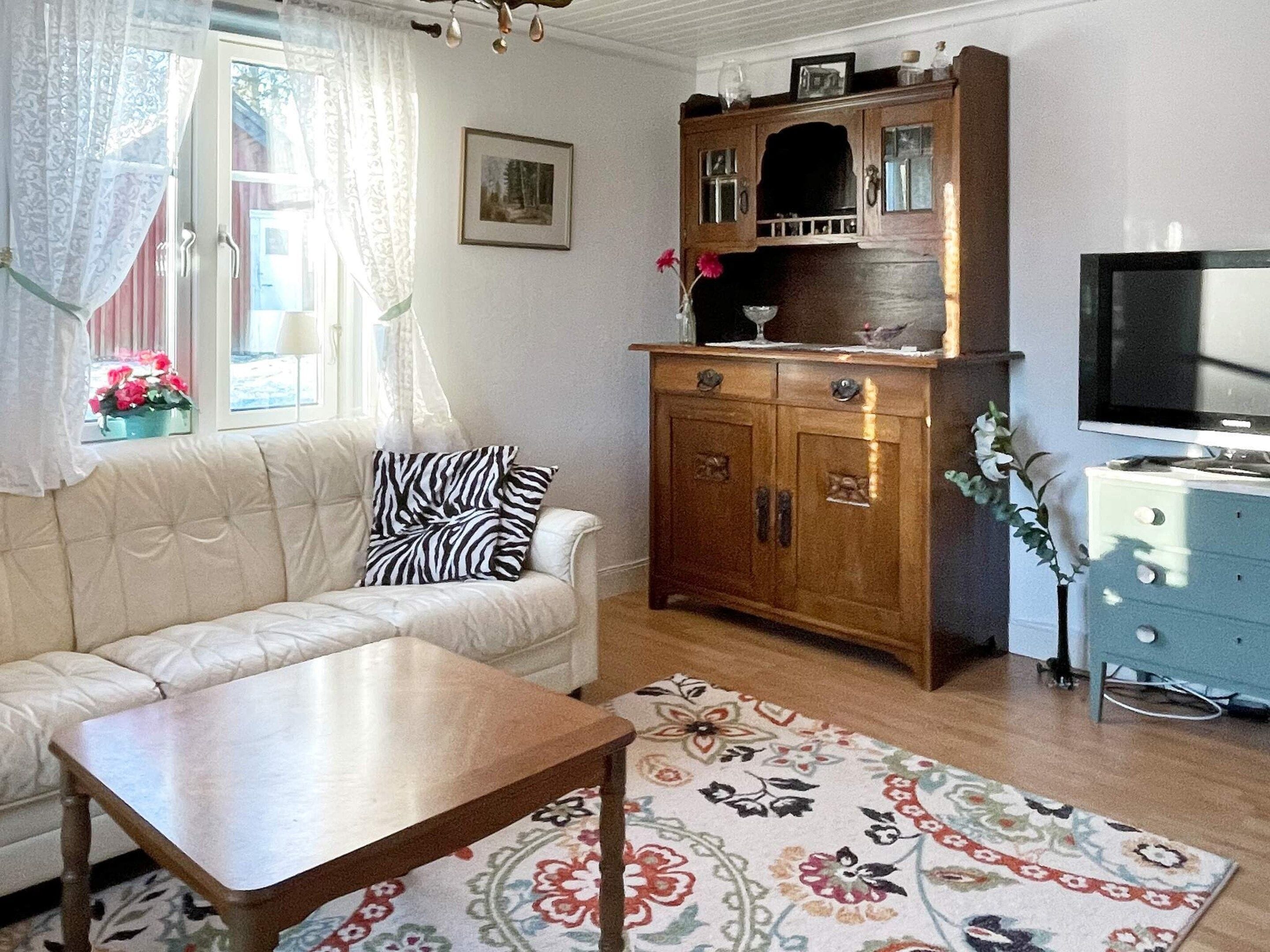 A living room with a sofa, a wooden cabinet, a television, and a floral rug.
