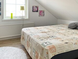 A bedroom with a bed, a window, a radiator, and a white rug. - 6 Person Holiday Home in Lidkoping (Lidköping)
