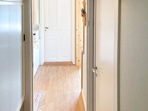 A hallway with a wooden floor, a white door, and a small rug. - 6 Person Holiday Home in Lidkoping (Lidköping)