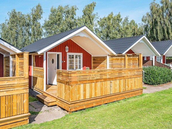 A row of wooden cabins with a red exterior, each featuring a door and a window. - 4 Person Holiday Home in Lottorp (Byxelkrok)