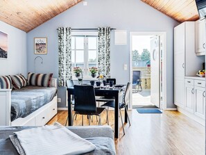 Une pièce chaleureuse avec un lit en mezzanine, un coin repas avec une table et des chaises, et un coin cuisine avec des placards et un comptoir.