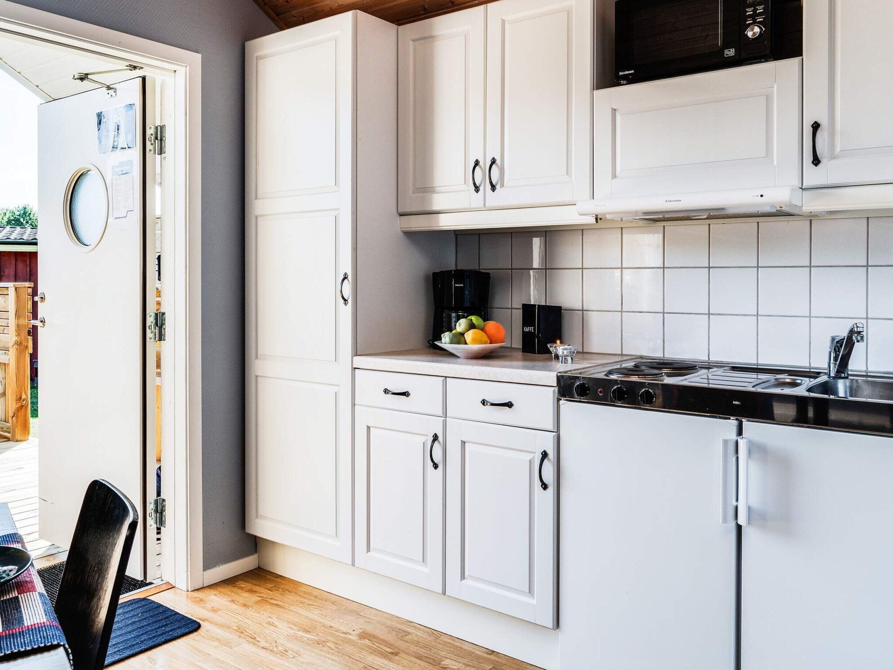 Una cocina moderna con armarios blancos, una estufa negra y un frutero pequeño sobre la encimera.
