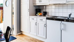 A modern kitchen with white cabinetry, a black stove, and a small fruit bowl on the counter. - 4 Person Holiday Home in Lottorp (Byxelkrok)