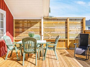 An outdoor patio with a wooden deck, a table with chairs, and a wooden fence. - 4 Person Holiday Home in Lottorp (Byxelkrok)