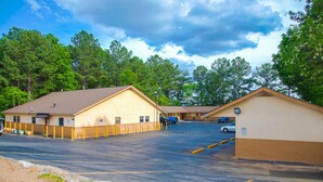 A parking lot with a building that has a yellow exterior and a brown roof. - OYO Hotel I-20 Decatur, East Atlanta (Decatur)