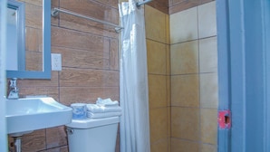 A bathroom with a white sink, toilet, and shower area. - OYO Hotel I-20 Decatur, East Atlanta (Decatur)