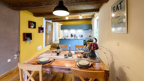 A dining area with a wooden table set for four, a pendant light, and a kitchen in the background. - Ackerbürgerhof Ballstraße 18 (Quedlinburg)
