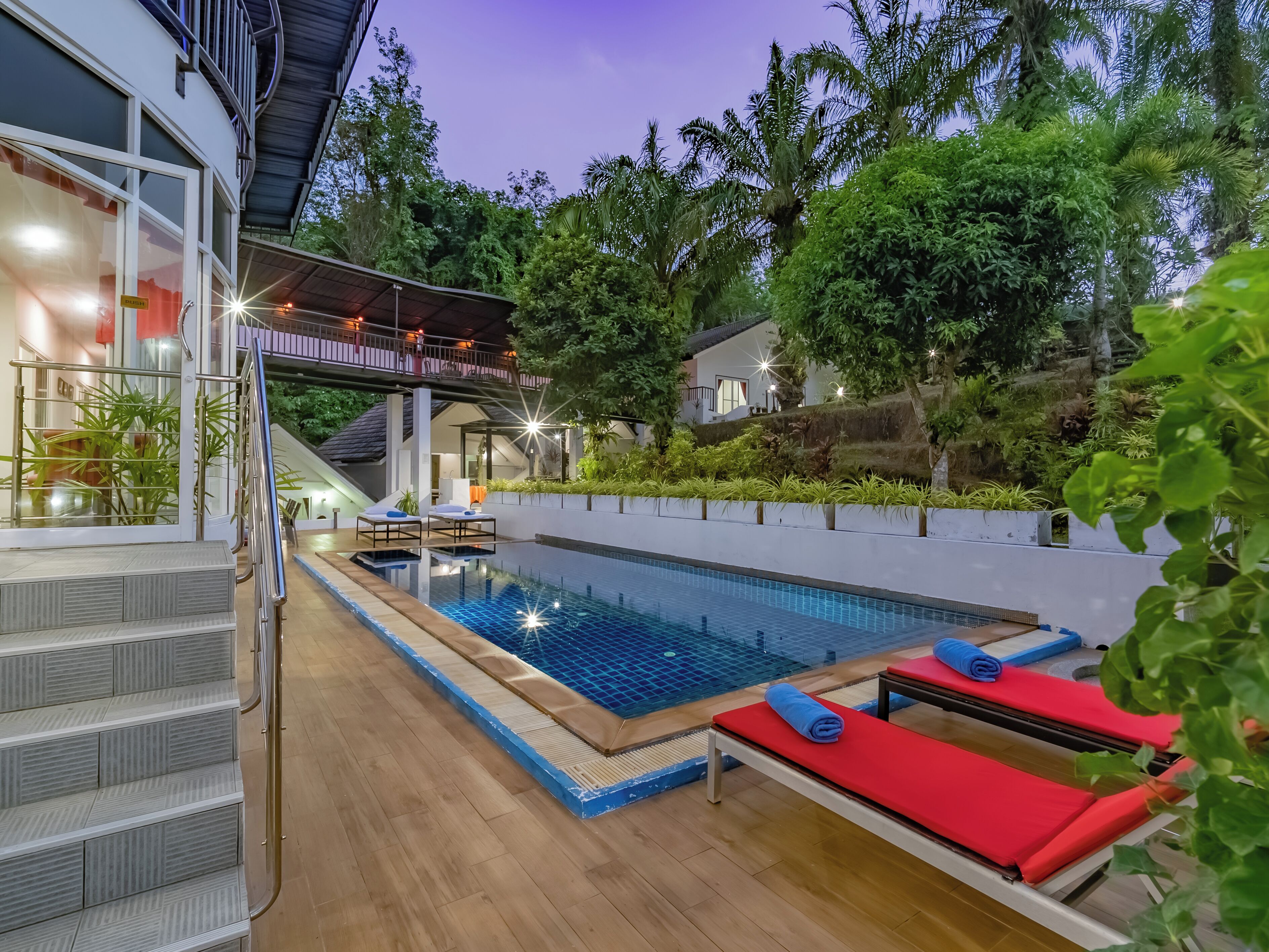 A swimming pool with steps leading to a covered area, lounge chairs, and a staircase.