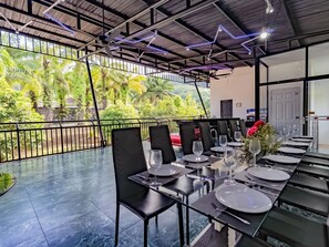 Un restaurante con terraza, sillas negras y mesas dispuestas con platos y copas de vino.