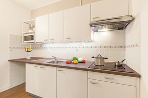 A kitchen with white cabinets, a microwave, a sink, and a stove.