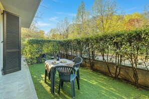 Eine Terrasse im Freien mit Tisch und Stühlen, einer Weinflasche und einem Teller Essen.