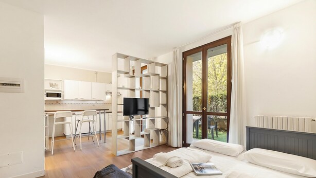 Une chambre d’hôtel moderne équipée d’un lit, d’une télévision, d’un coin cuisine et d’un balcon avec vue.