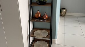 A wooden shelf with decorative items and a welcome sign on a teal wall. - 77 On independence Avenue (Windhoek)