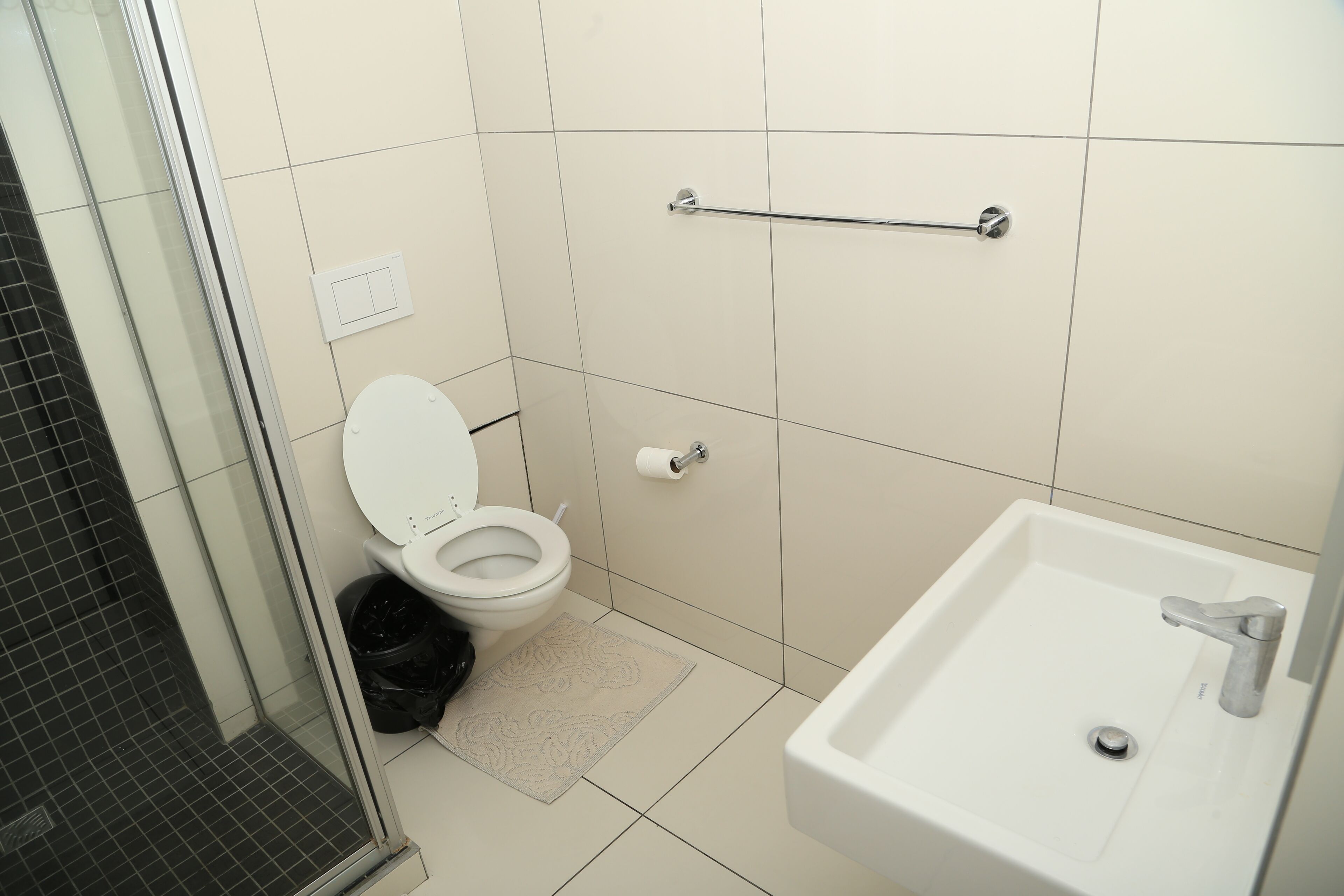 A bathroom with a toilet, a sink, a towel rack, and a shower.