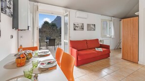 Un comedor con una mesa lista para dos personas, un sofá rojo y vistas al exterior.