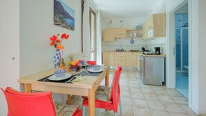 A compact kitchen with a dining area, a refrigerator, and a view of the sea through the window. - Porto Letizia Napoli 6, Porlezza, Italy (Porlezza)