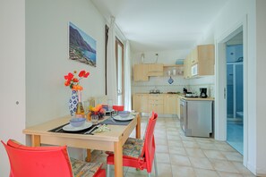 Une cuisine compacte avec un coin repas, un réfrigérateur et une vue sur la mer par la fenêtre.