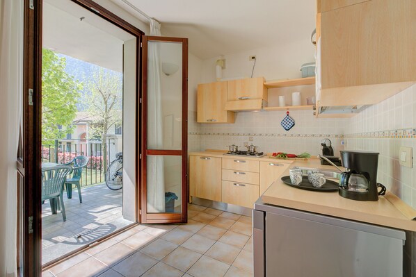 A kitchen with wooden cabinets, a coffee maker, and a dining area with chairs and a table.