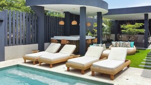 Un área de piscina con sillones de descanso y una zona de estar cubierta.