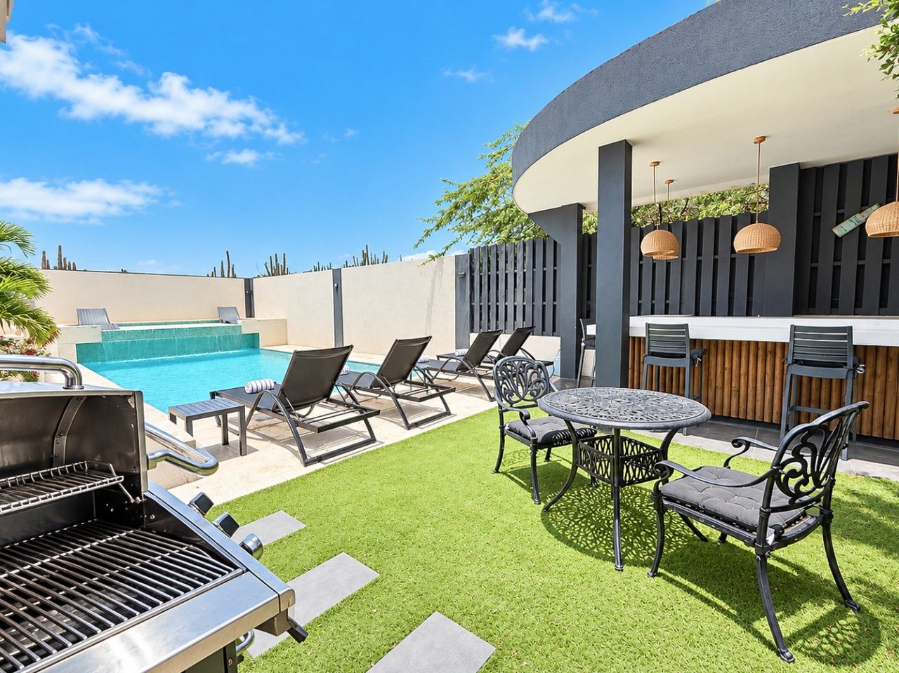 Your private Aruba escape awaits! Enjoy a sparkling swimming pool, comfortable sun loungers, an inviting outdoor bar, and a beautifully designed tropical courtyard made for relaxation.