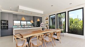 Cocina moderna con una isla central, iluminación colgante y vistas al exterior.