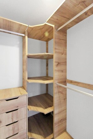 A corner room with a built-in wooden shelving unit and a small desk with drawers.
