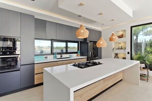 Una cocina moderna con una isla central, electrodomésticos integrados e iluminación colgante.