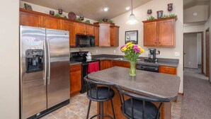 A modern kitchen with stainless steel appliances, wooden cabinets, and a central island with bar stools. - East side single family home near Harmadon ball fields (Sioux Falls)