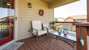 A covered porch with two white chairs, a glass table, a lantern, and a wreath on the wall. - East side single family home near Harmadon ball fields (Sioux Falls)