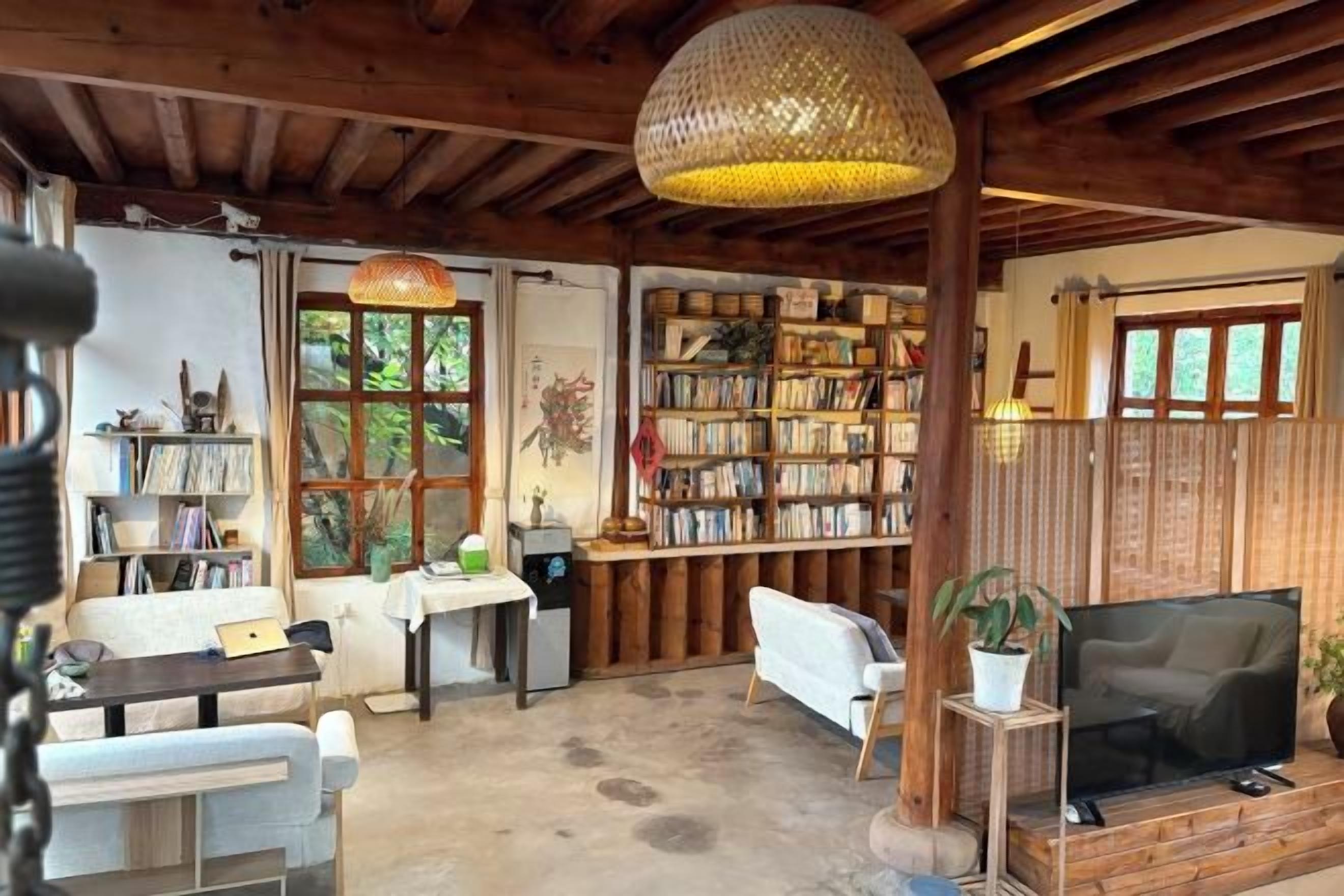 A cozy living room with a bookshelf, a television, and a dining area.