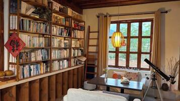 A cozy room with a bookshelf, a telescope, and a window with a view.