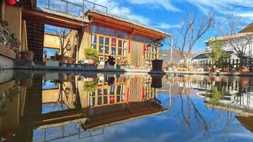 A traditional building with a reflection in the water, a clear sky, and a calm atmosphere.