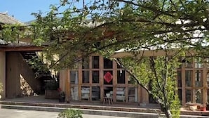A traditional building with a tiled entrance, a small outdoor seating area with chairs and tables, and a decorative red sign above the entrance. - Shaxi Serenity Residence (Jianchuan)