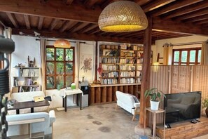 A cozy room with a wooden ceiling, a bookshelf, a sofa, a TV, and a dining area. - Shaxi Serenity Residence (Jianchuan)