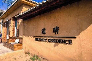 A building with a sign that reads "ERINITY RESIDENCE" and a wooden bench outside. - Shaxi Serenity Residence (Jianchuan)