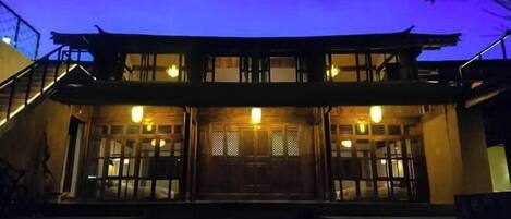 A traditional building with a wooden facade, large windows, and a staircase leading to the entrance.