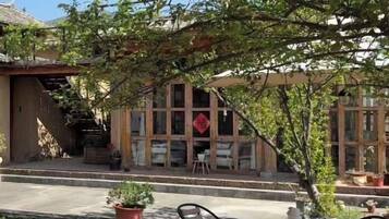 A traditional building with a tiled roof, a wooden staircase, and a seating area with tables and chairs.