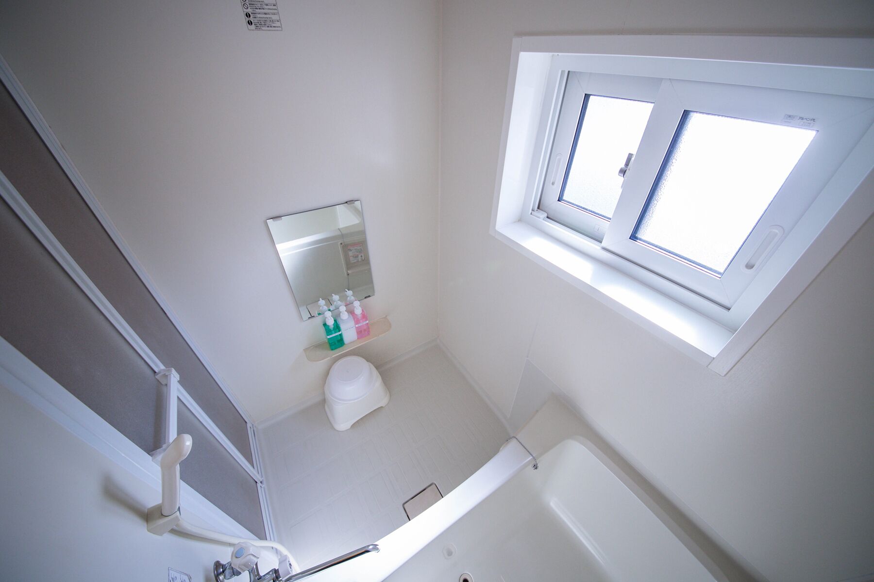 A bathroom with a toilet, a sink, a mirror, and a window.