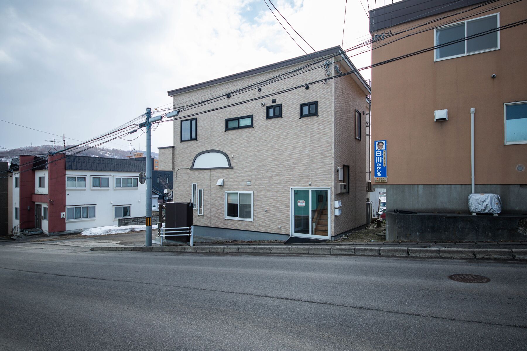 Un immeuble à plusieurs étages, doté d’une façade beige, d’une entrée bien visible et d’une enseigne bleue sur le côté droit.