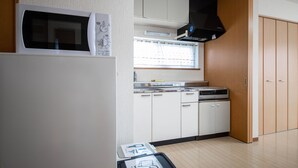 A compact kitchen with a microwave, stove, and cabinets. - SUMIYOSHI HOUSE ROOMB (Otaru)
