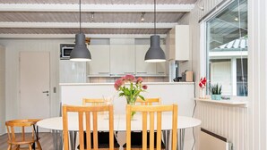 En matplats med ett runt bord, fyra trästolar, två hänglampor och en vas med blommor.