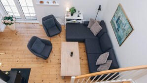 A modern living room with a sofa, chairs, a coffee table, a fireplace, and a staircase.